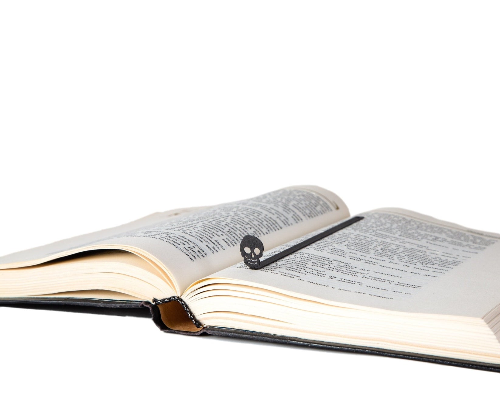 Grinning Skull metal bookmark resting on the pages of an open book