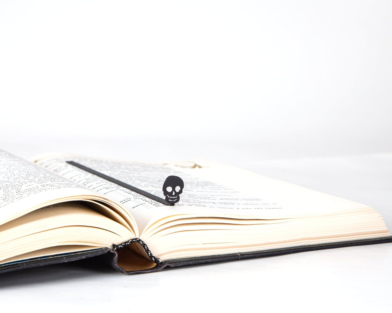 Grinning Skull metal bookmark marking a page in an open book