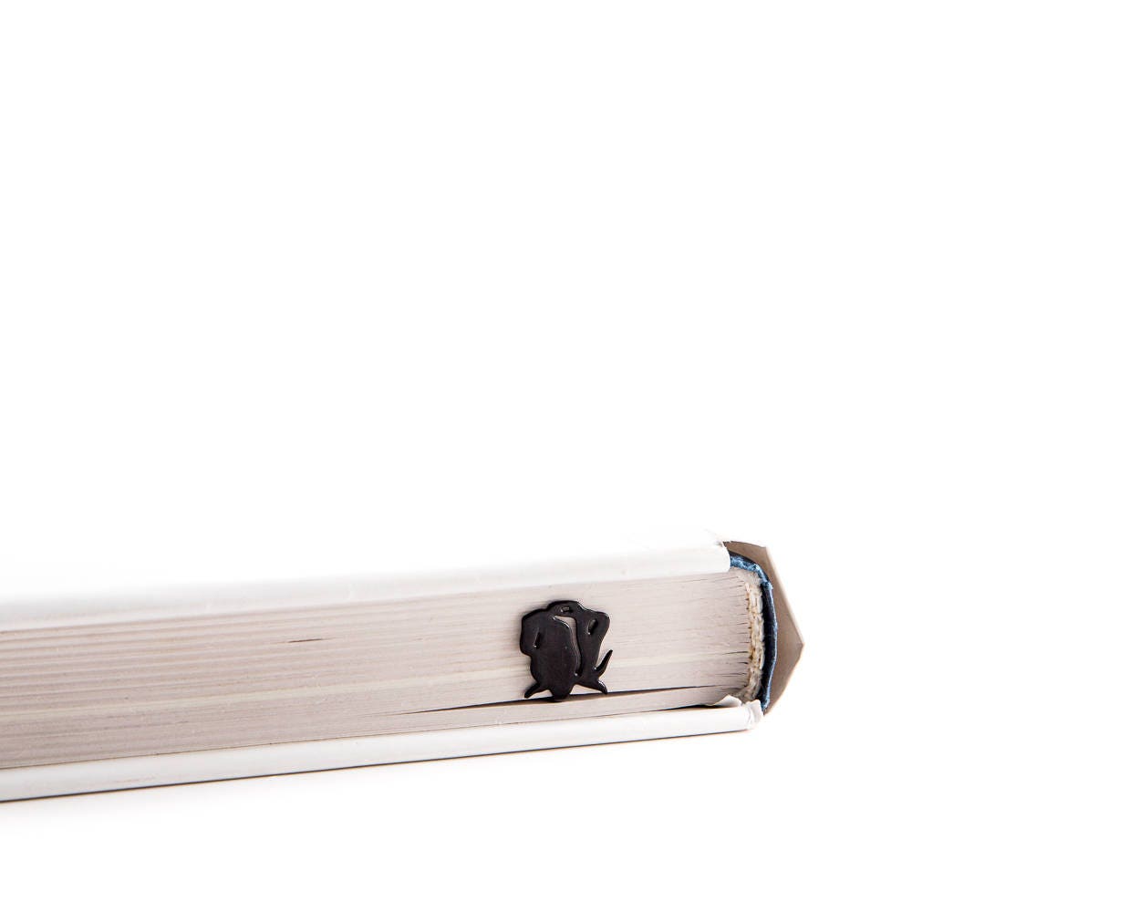 Gun with a Flower metal bookmark in a closed book, only its top showing above the pages