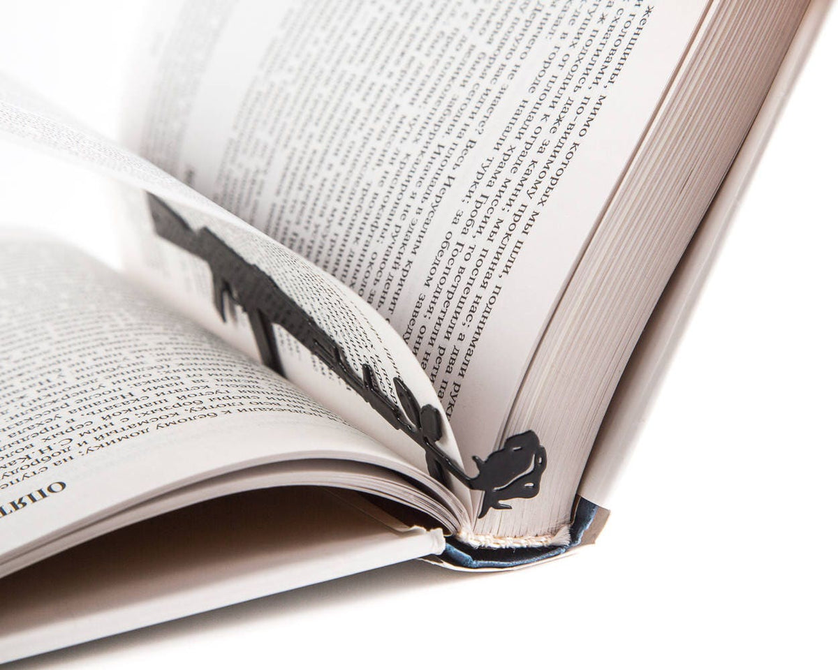 Gun with a Flower metal bookmark marking a page in an open book