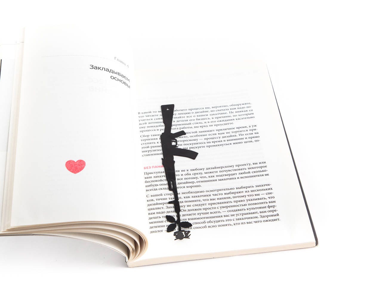 Gun with a Flower metal bookmark lying across the pages of an open book