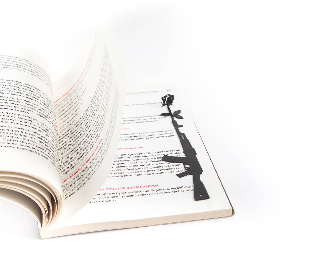 Gun with a Flower metal bookmark resting on the pages of an open book