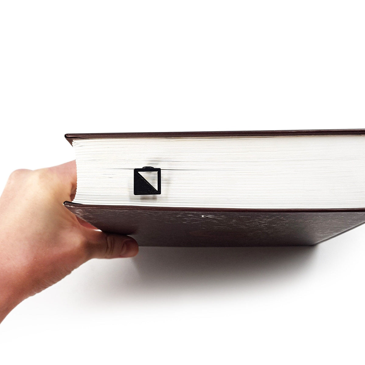 Half Square metal bookmark held up beside an open book