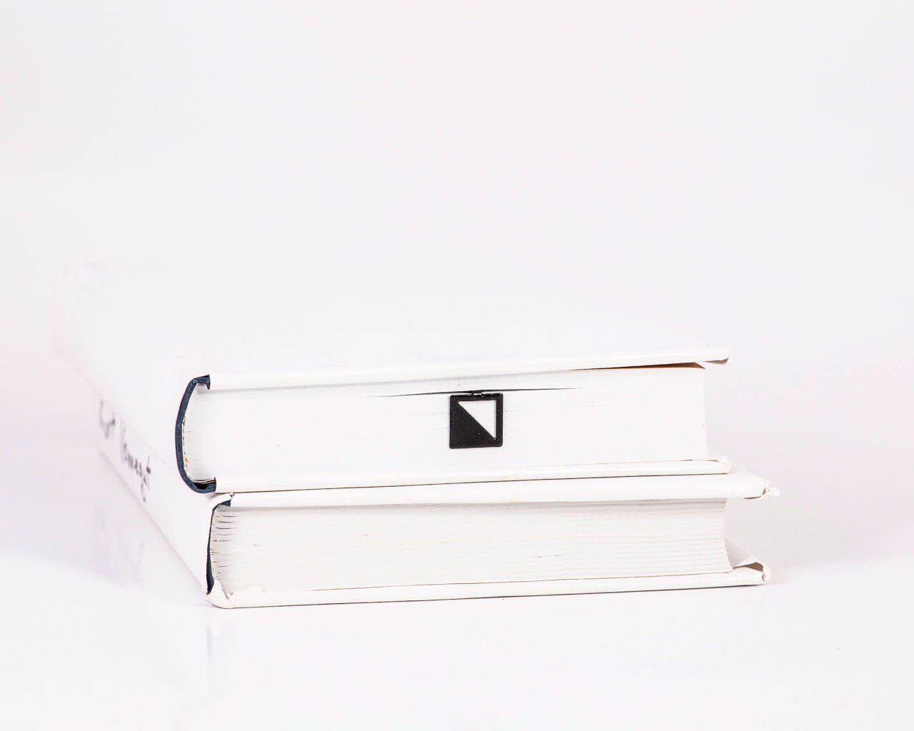 Half Square metal bookmark in a closed book, only its top showing above the pages