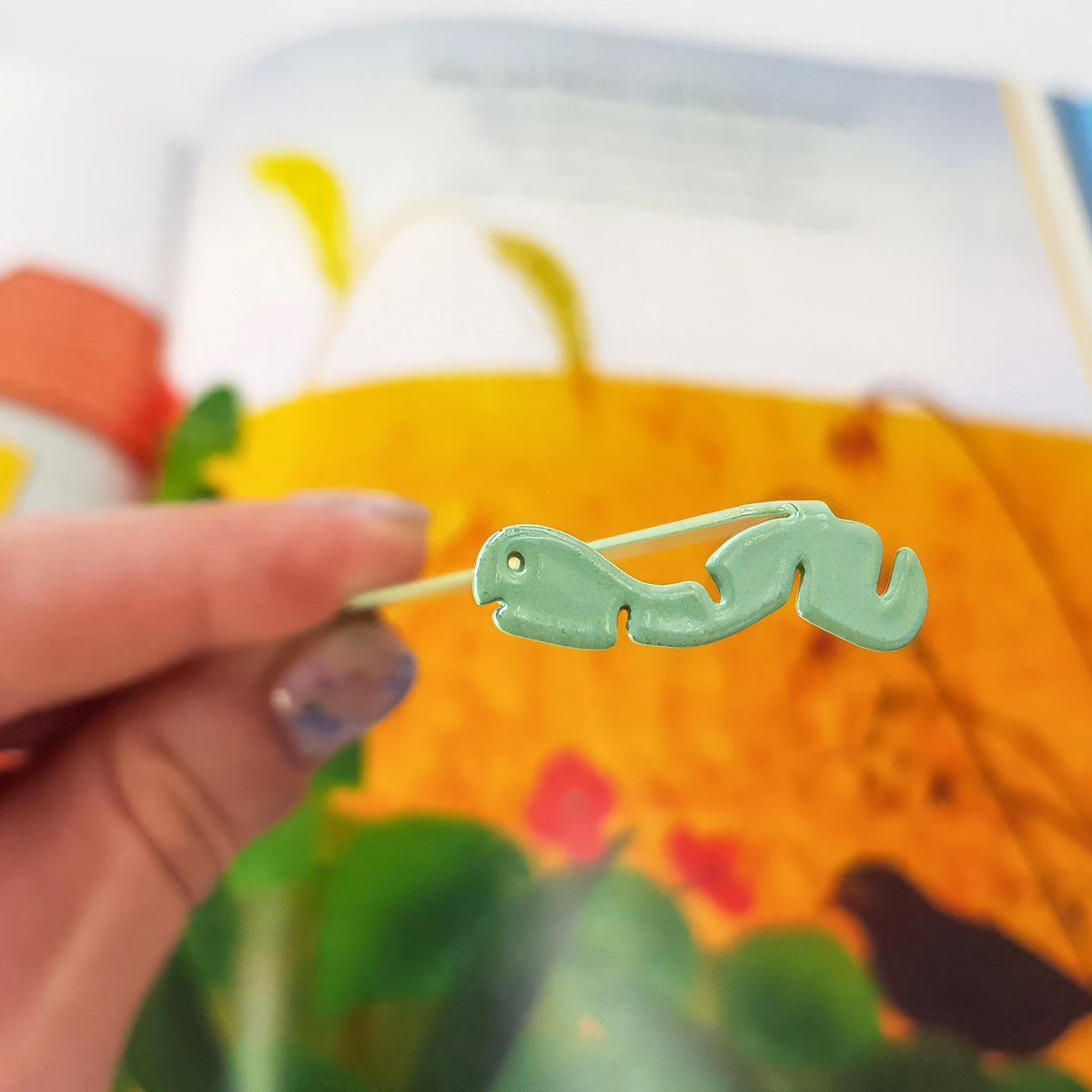 Happy metal bookmark in green placed on a colour illustration