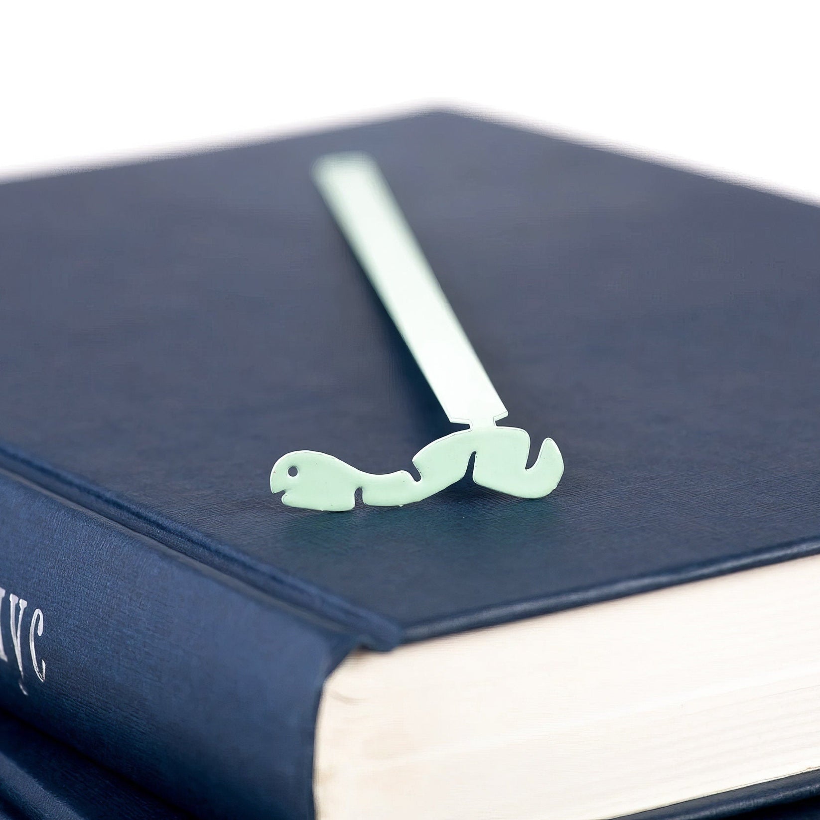 Happy metal bookmark in green in a closed book, only its top showing above the pages
