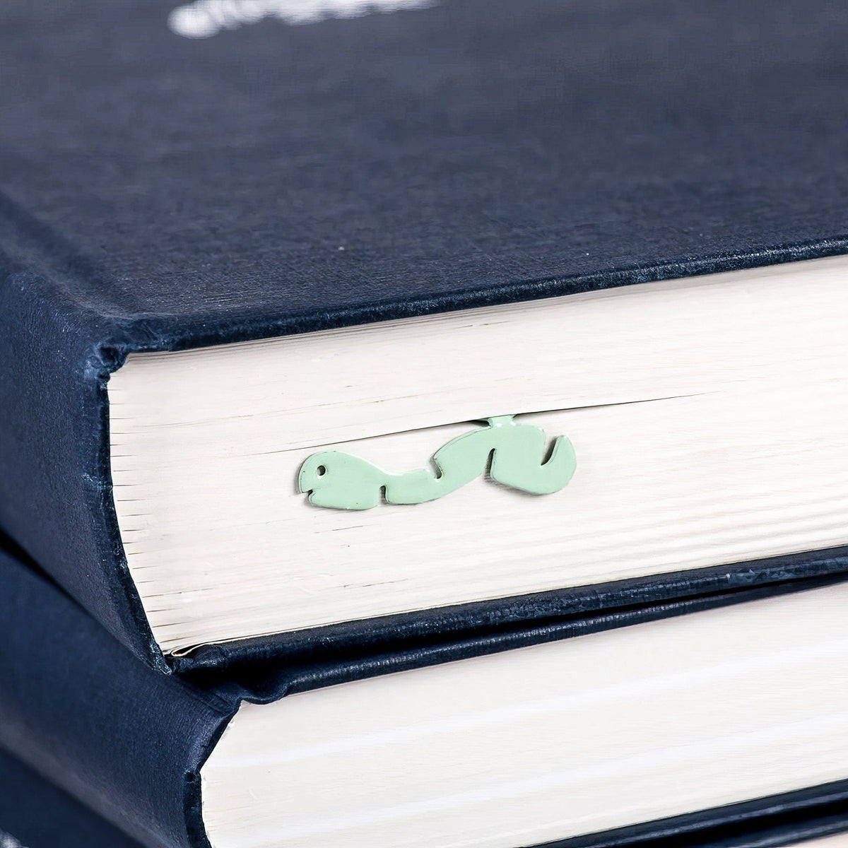 Happy metal bookmark in green clipped in a closed book, viewed from the side