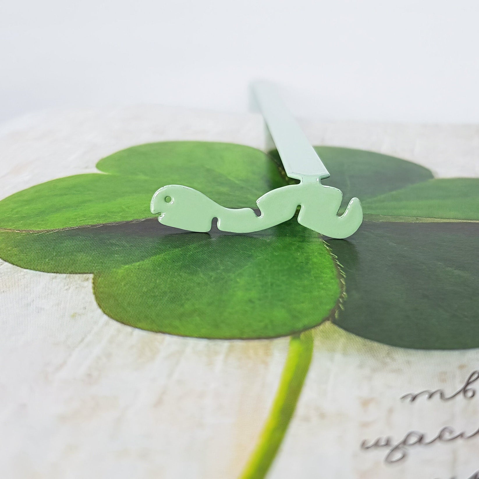 Happy metal bookmark in green on an illustrated page