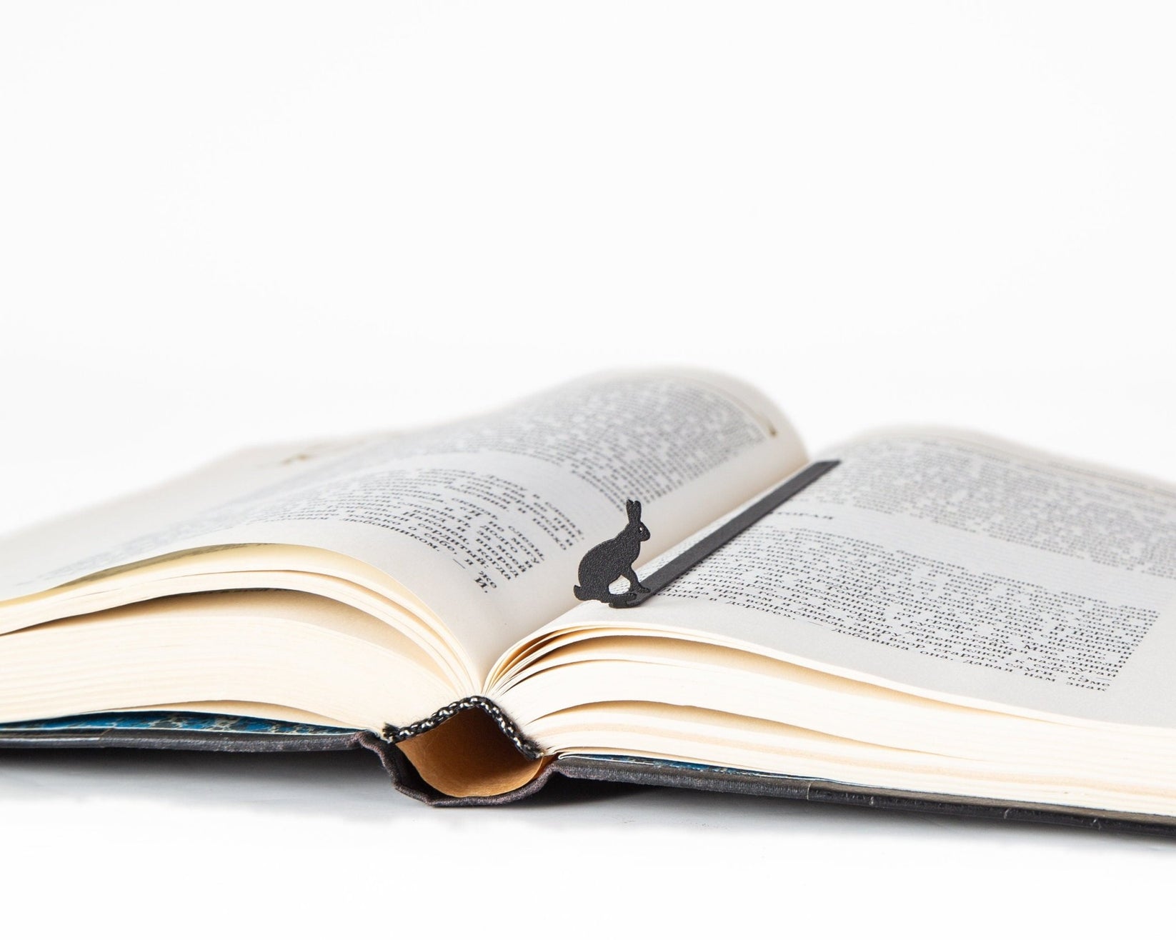 Hare metal bookmark marking a page in an open book