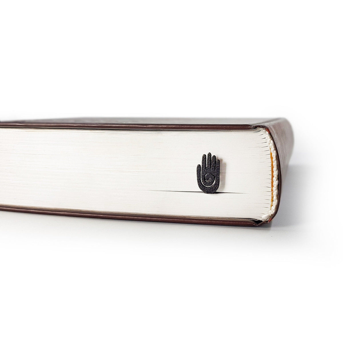 Healing Hand metal bookmark in a closed book, only its top showing above the pages