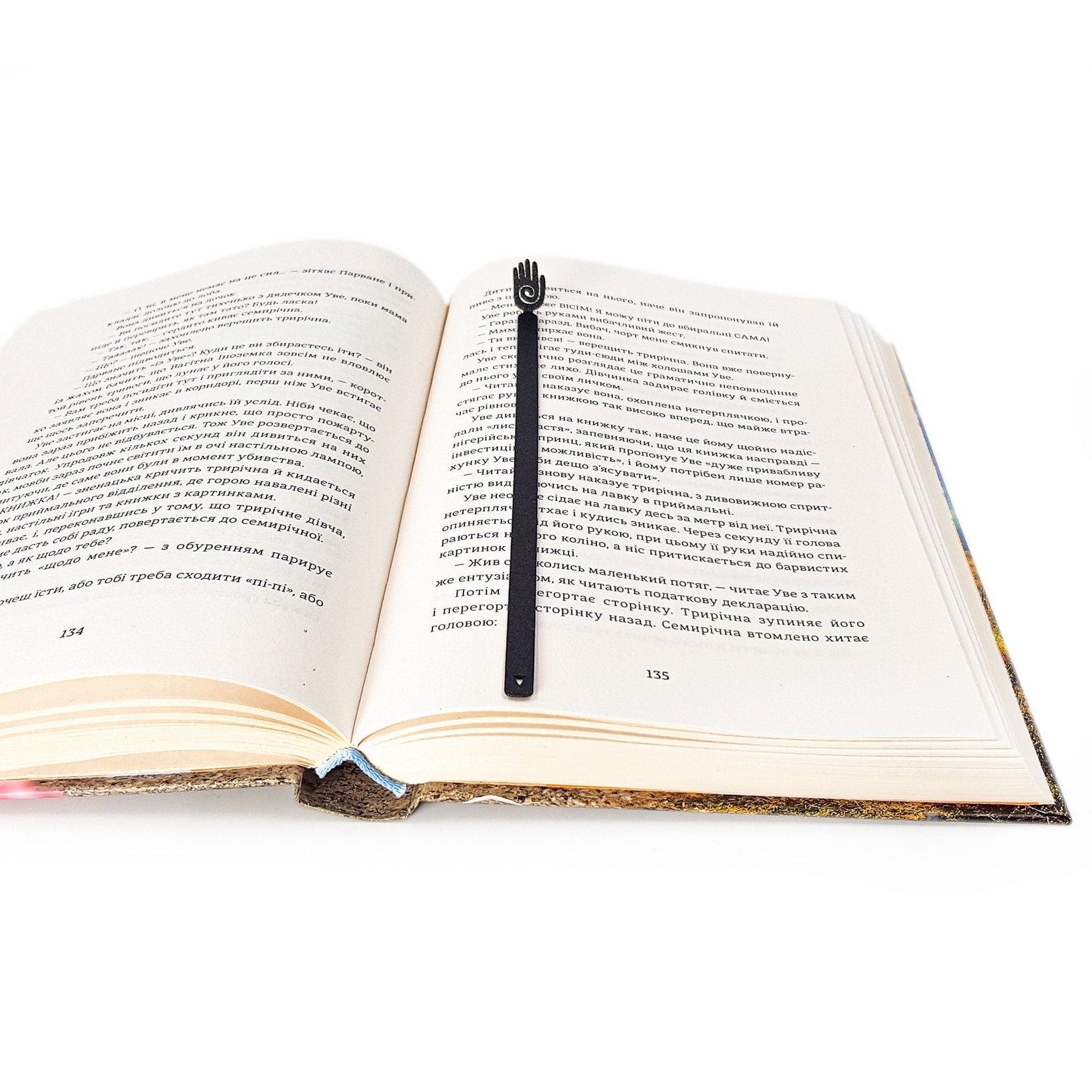 Healing Hand metal bookmark marking a page in an open book