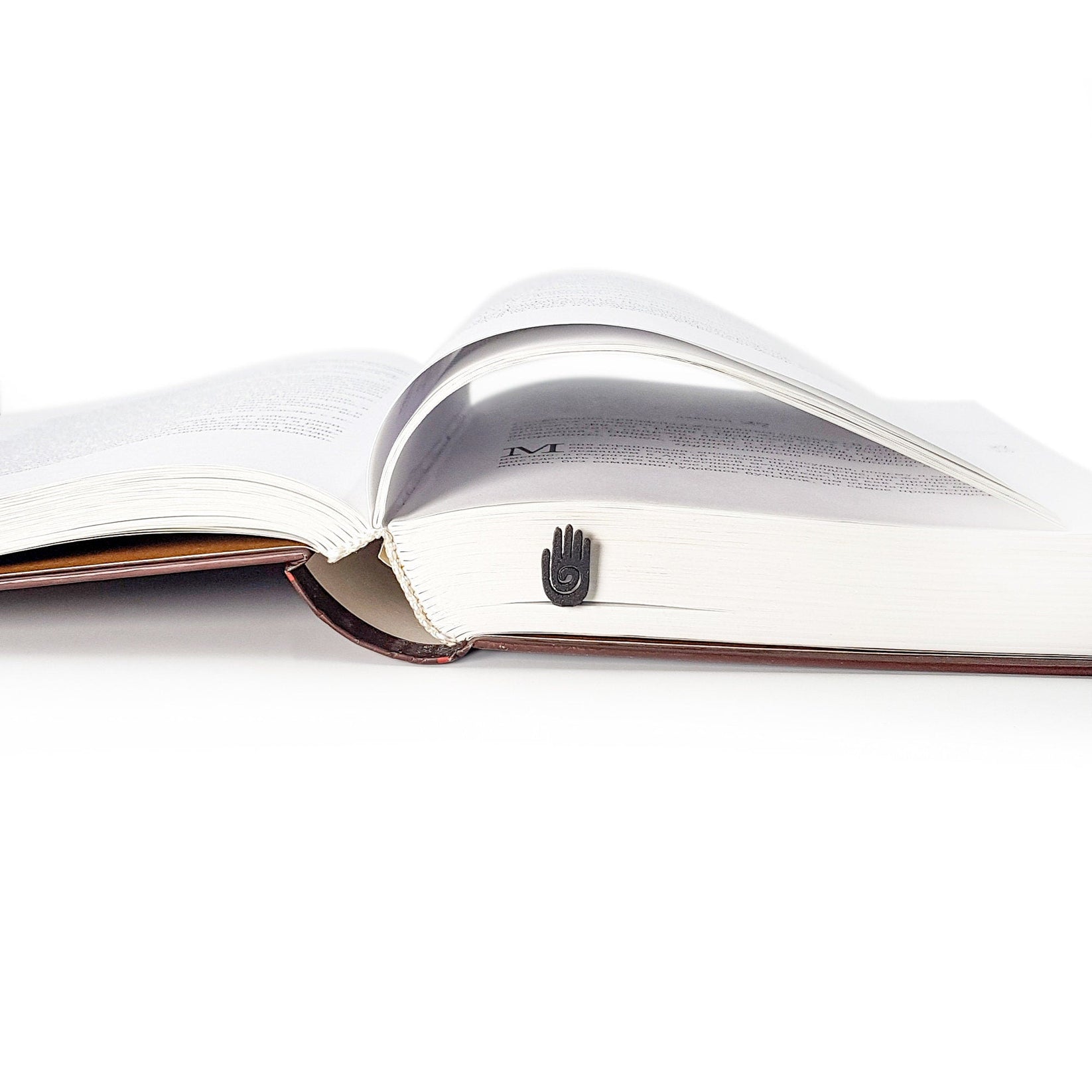 Healing Hand metal bookmark set into the gutter of an open book