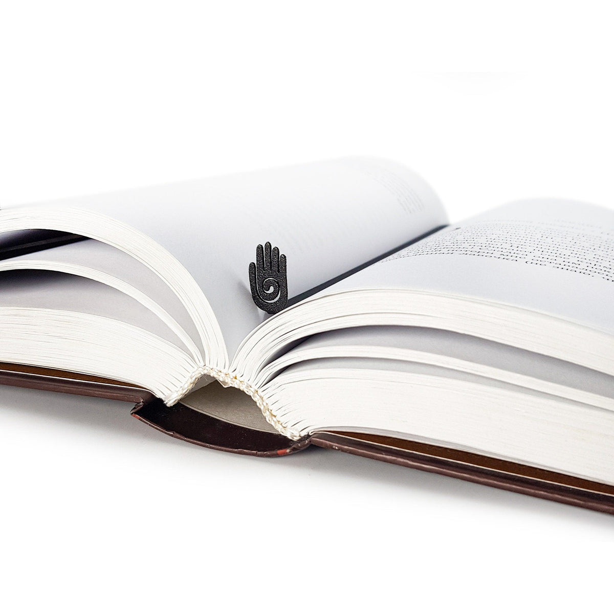 Healing Hand metal bookmark lying across the pages of an open book