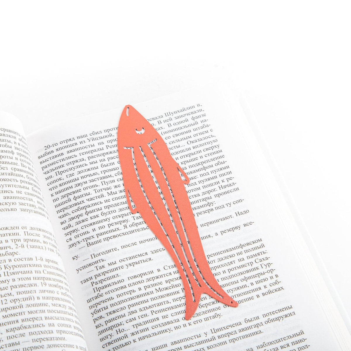 Herring metal bookmark in red resting on the pages of an open book