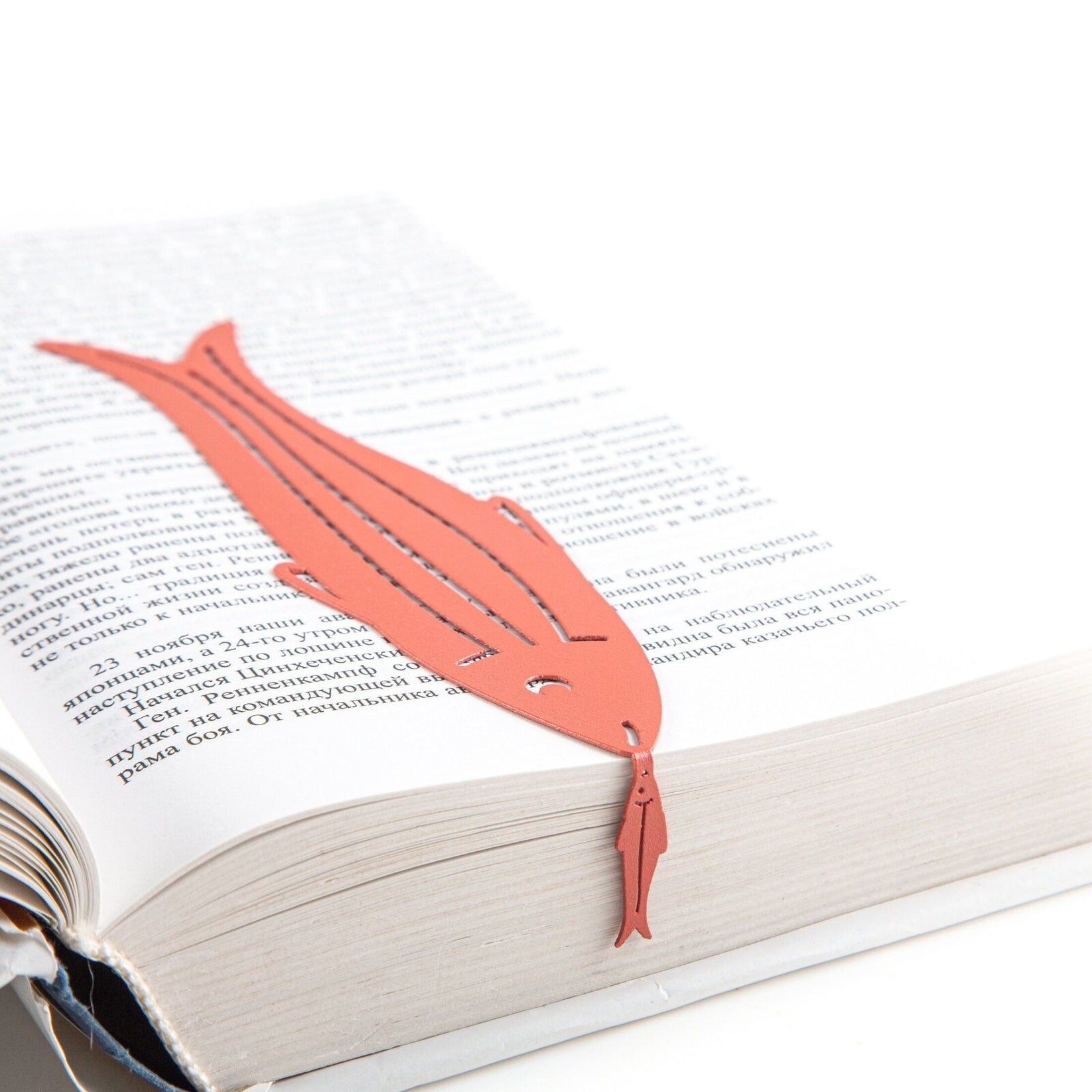Herring metal bookmark in red set into the gutter of an open book