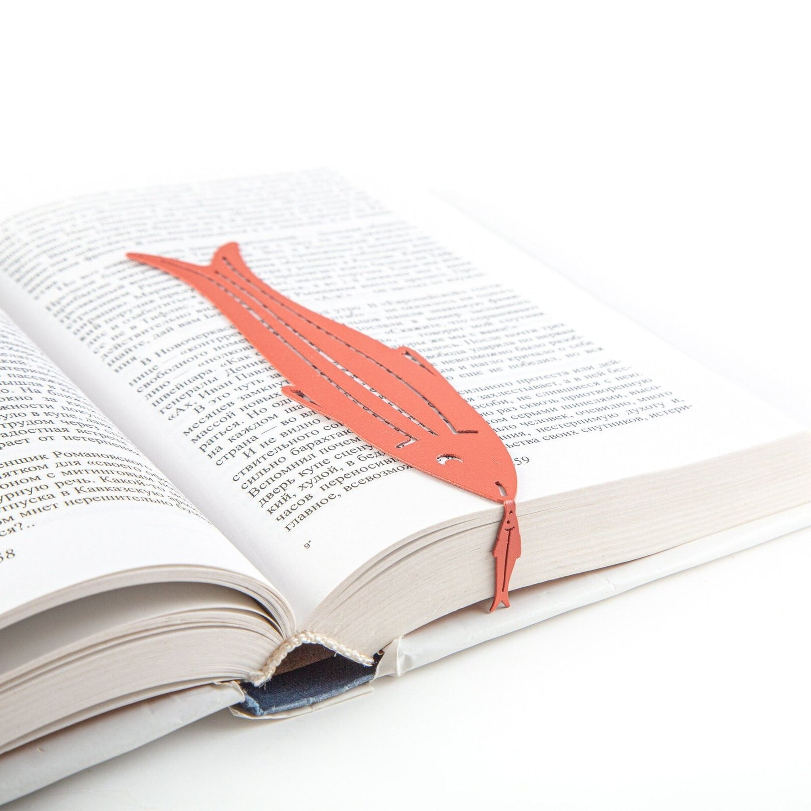 Herring metal bookmark in red resting on the pages of an open book, view 5