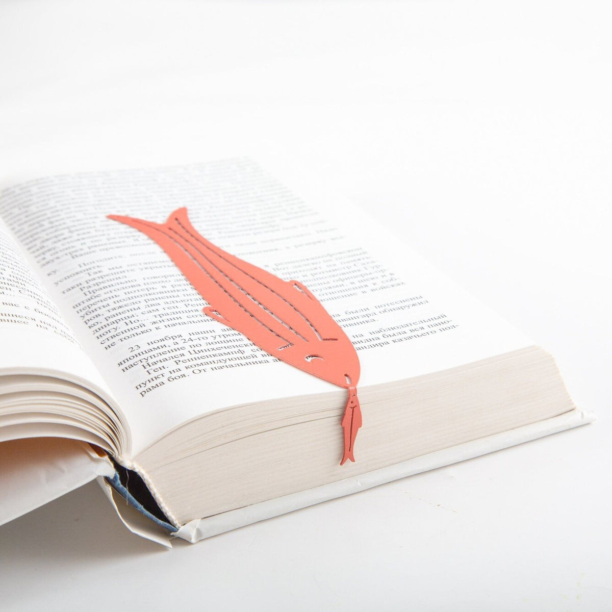Herring metal bookmark in red marking a page in an open book