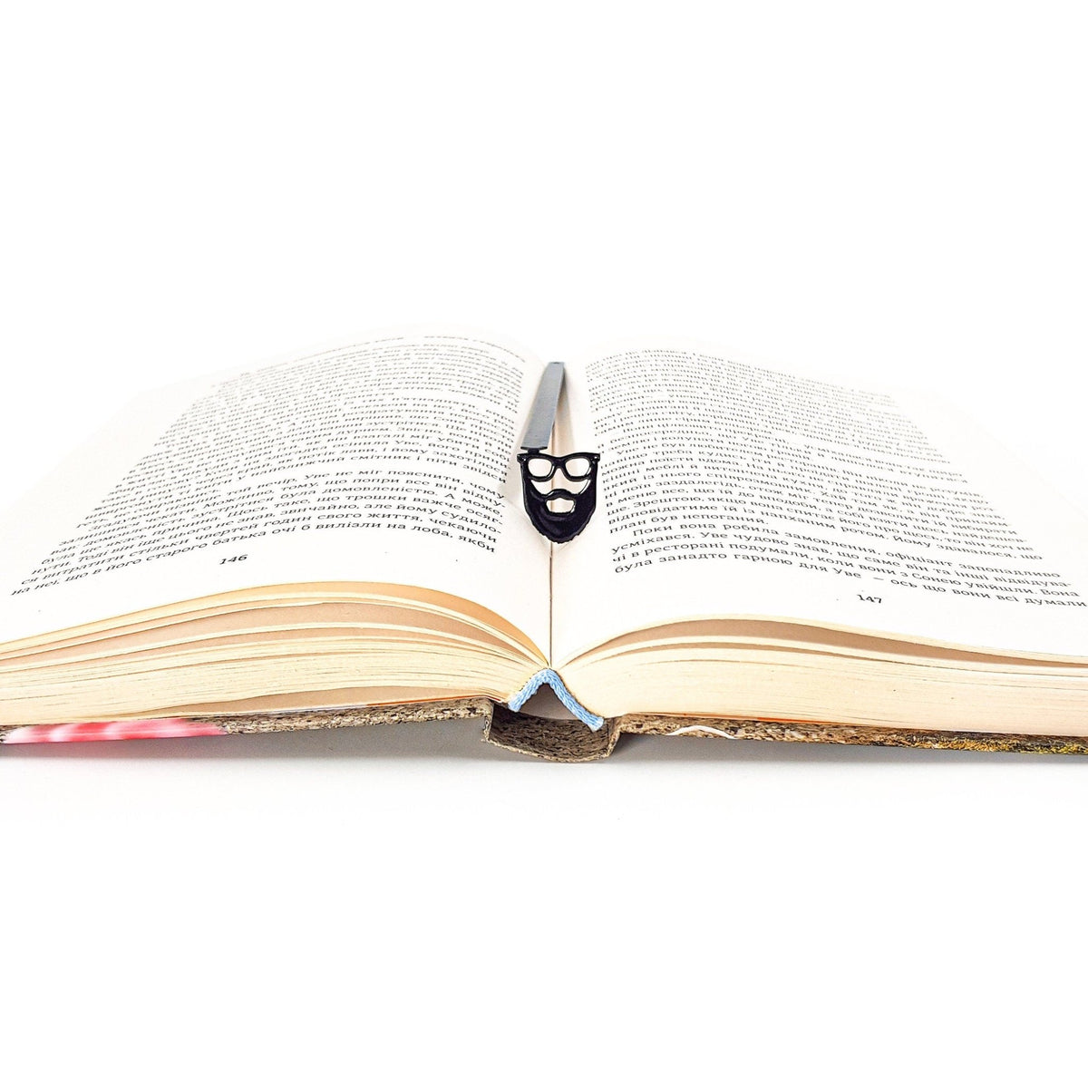 Hipster metal bookmark marking a page in an open book