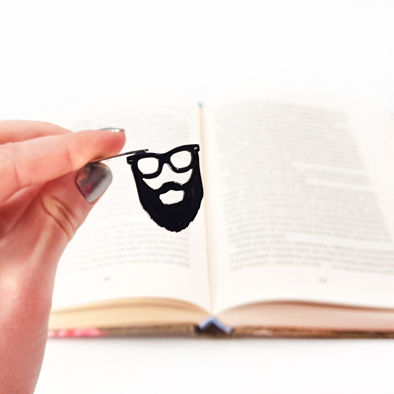 Hipster metal bookmark held in a hand above an open book