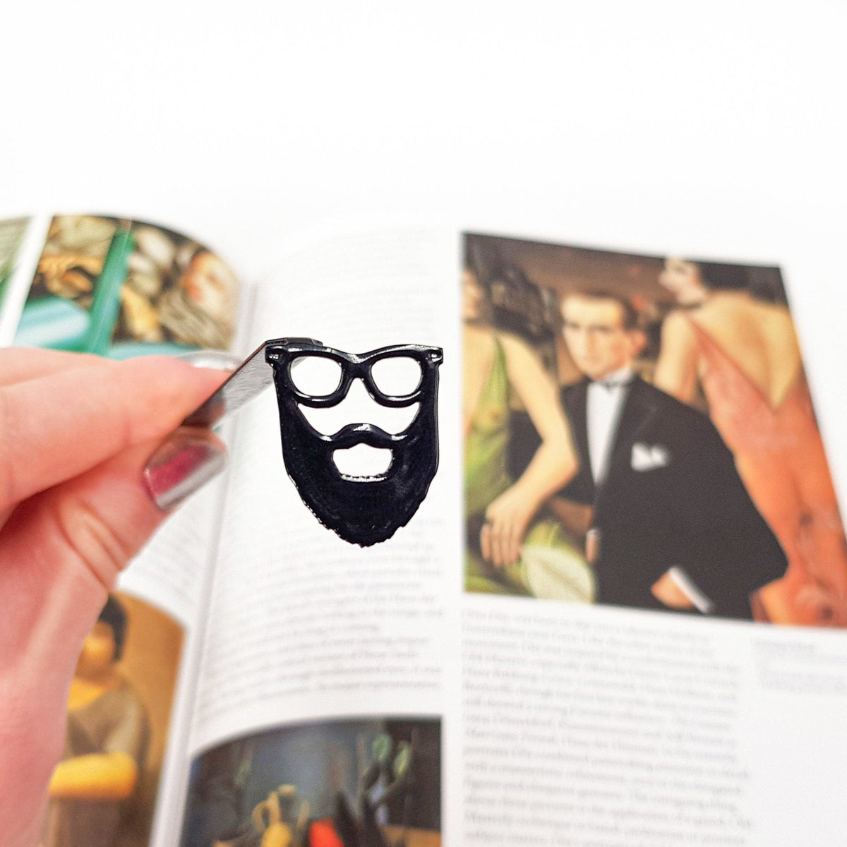Hipster metal bookmark marking a page in an illustrated book