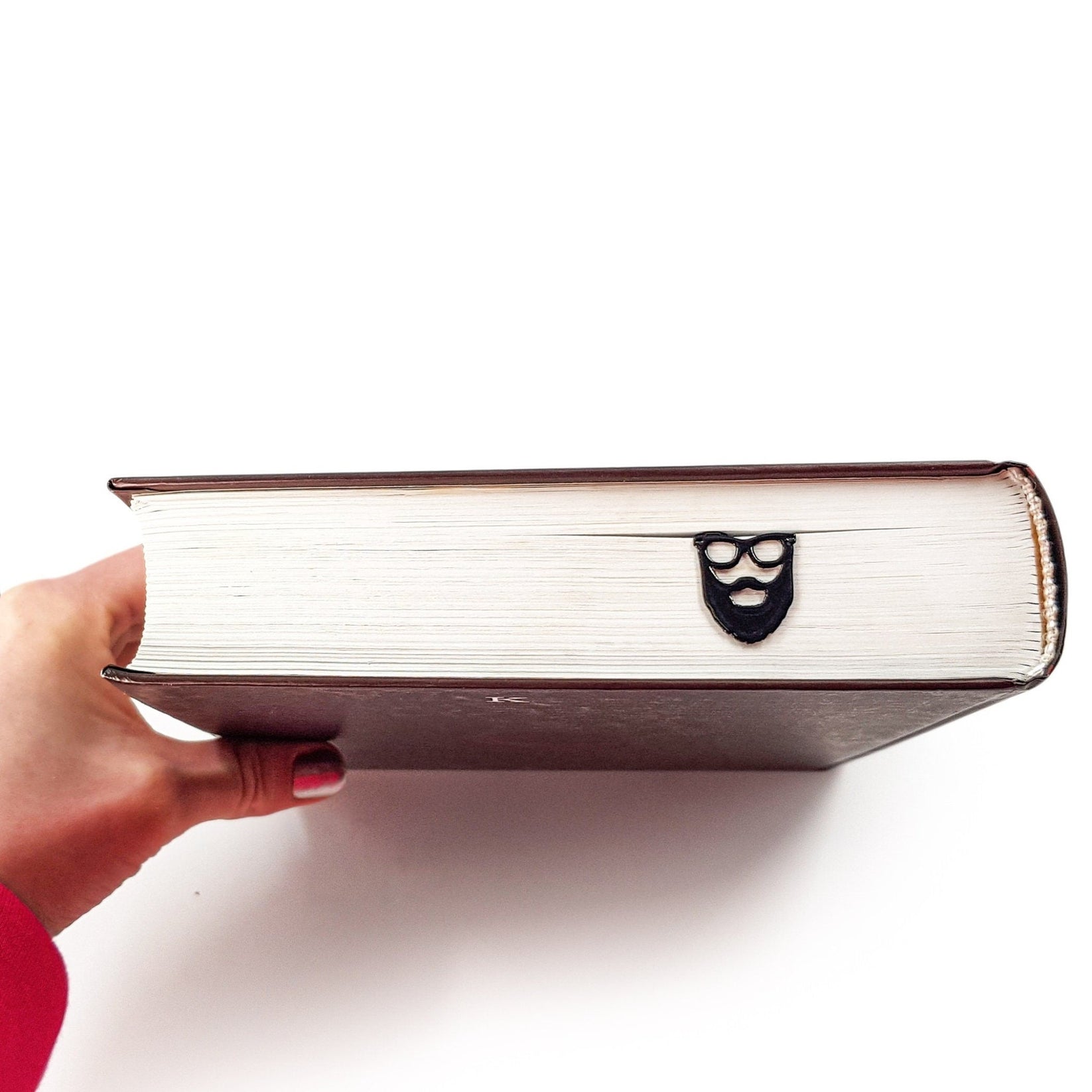 Hipster metal bookmark held up beside an open book