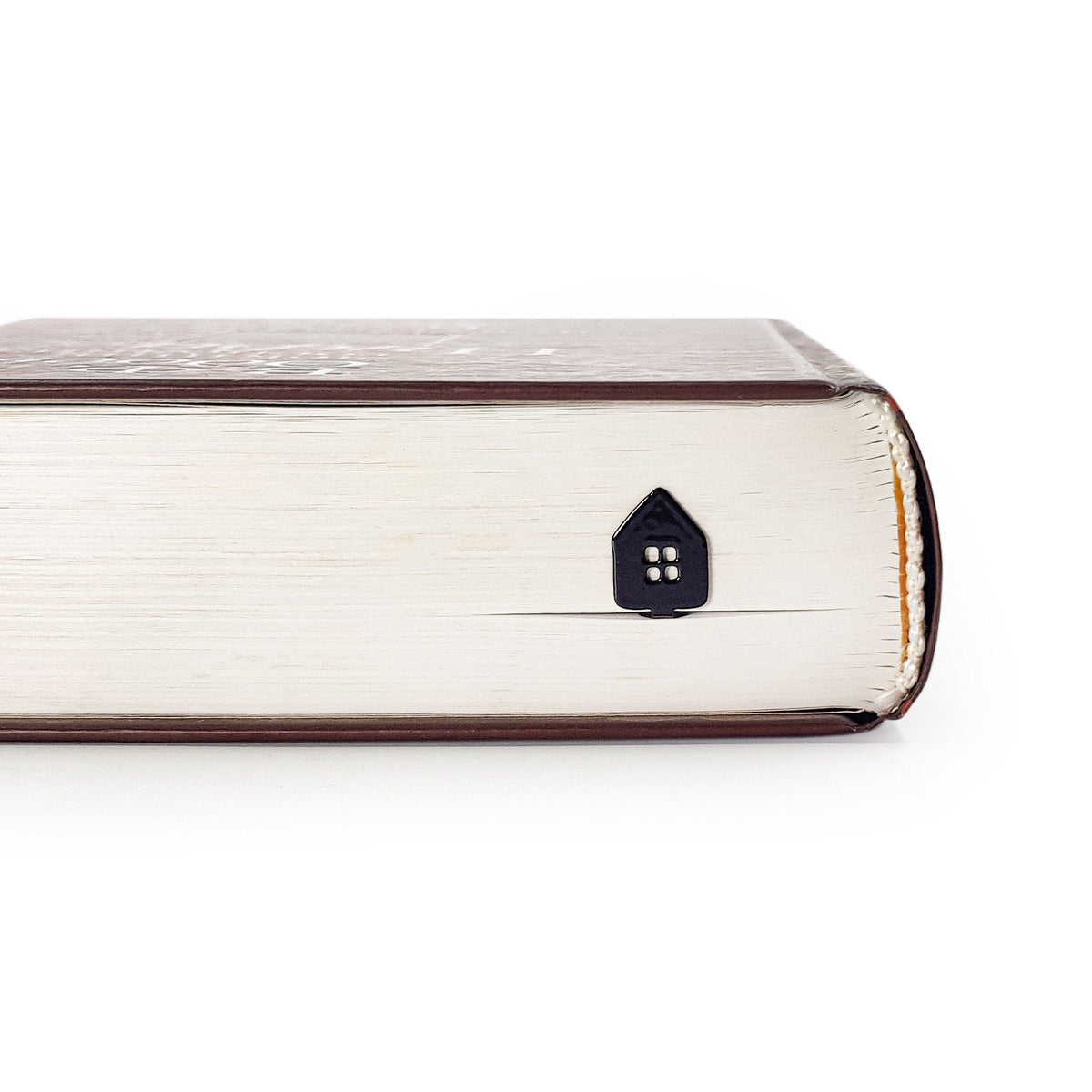 Home Sweet Home metal bookmark in a closed book, only its top showing above the pages