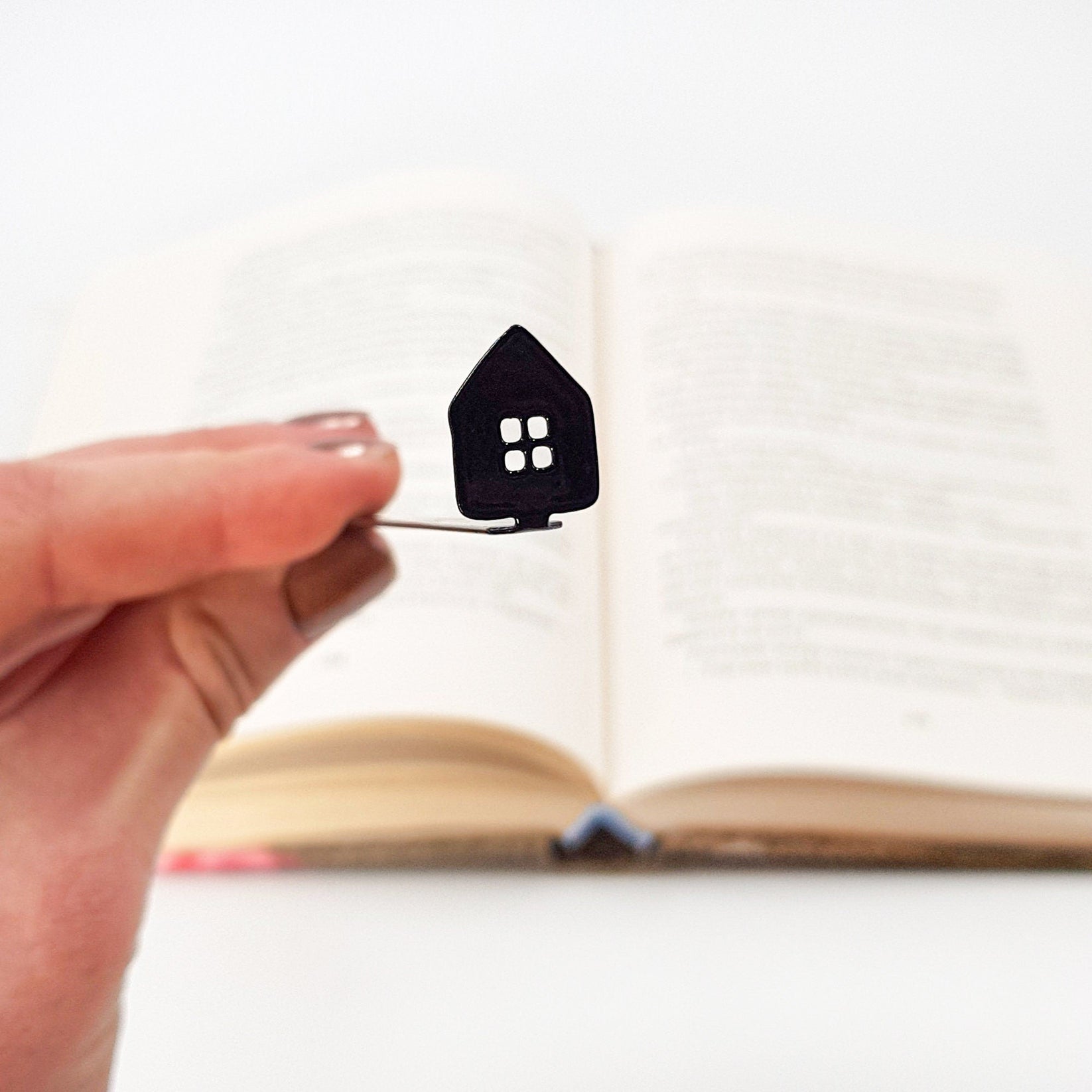 Home Sweet Home metal bookmark held in a hand above an open book