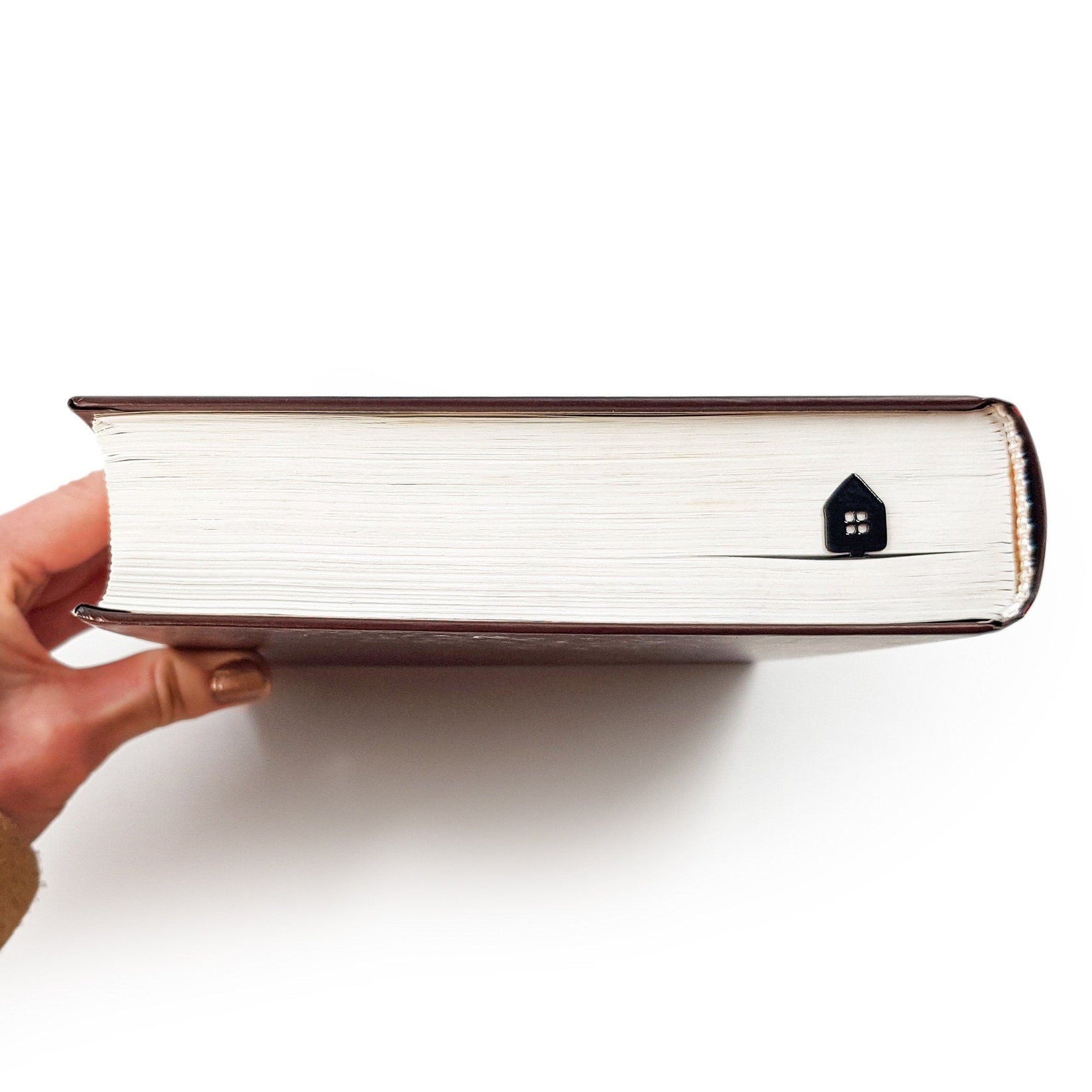 Home Sweet Home metal bookmark held up beside an open book