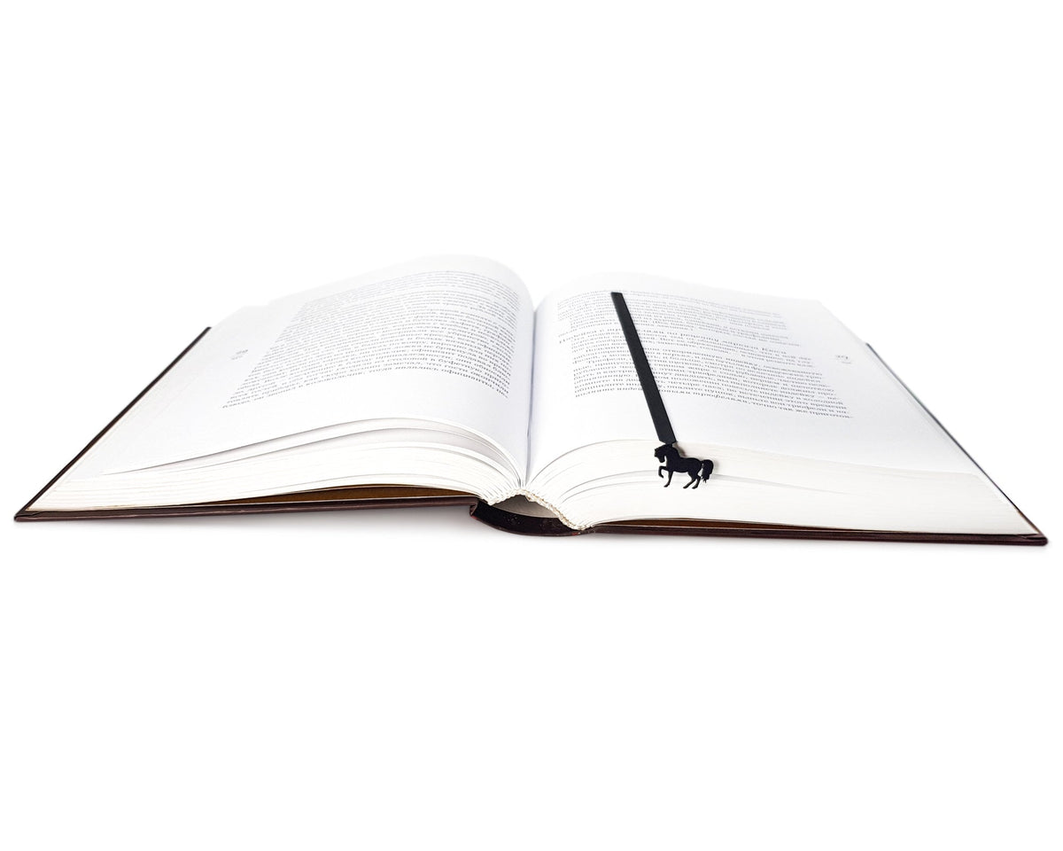 Horse metal bookmark resting on the pages of an open book