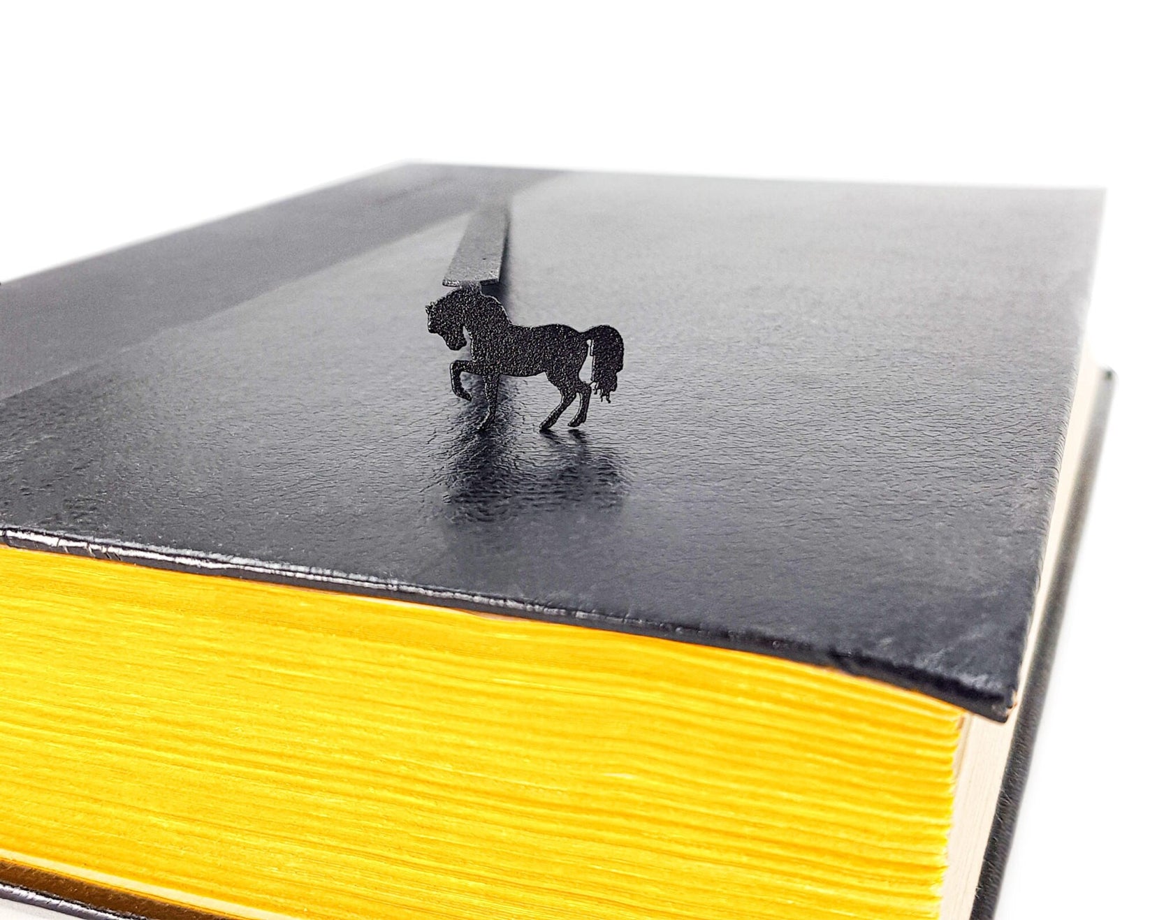 Horse metal bookmark seen from the edge of a closed book