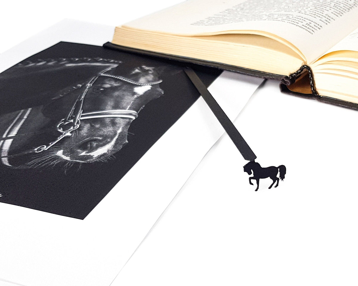 Horse metal bookmark marking a page in an illustrated book