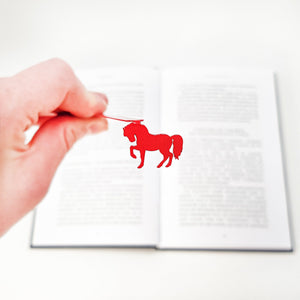 Hand holding a red horse bookmark. Designed and made in Cherkasy, Ukraine. Not mass-produced.