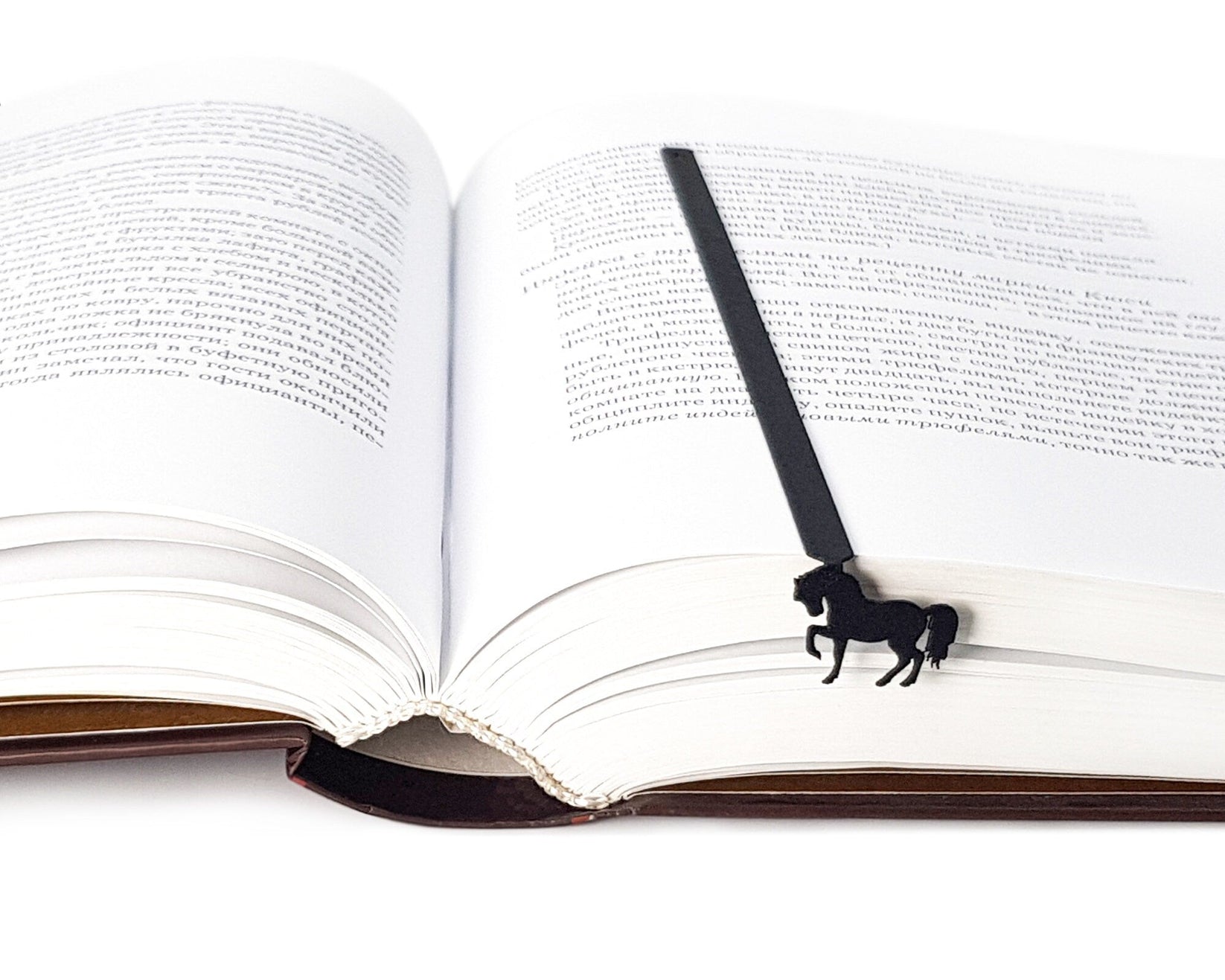 Horse metal bookmark lying across the pages of an open book
