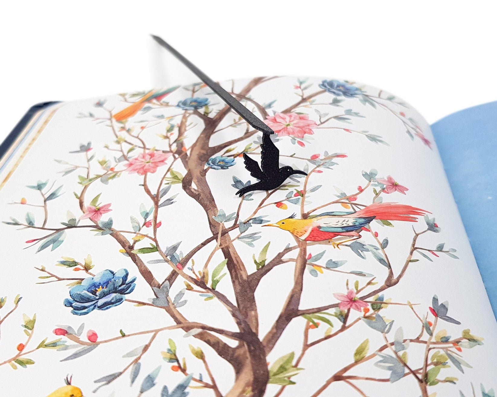 Hummingbird metal bookmark marking a page in an illustrated book
