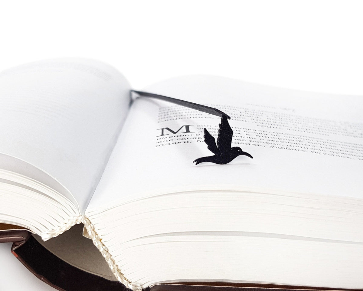 Hummingbird metal bookmark marking a page in an open book