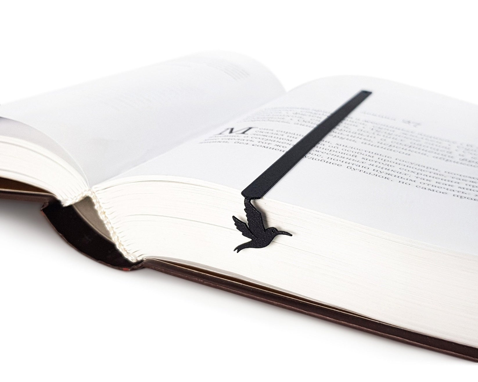 Hummingbird metal bookmark lying across the pages of an open book