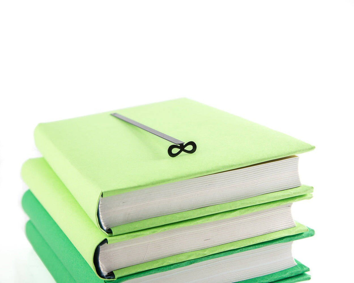 Infinity metal bookmark lying on a stack of white books