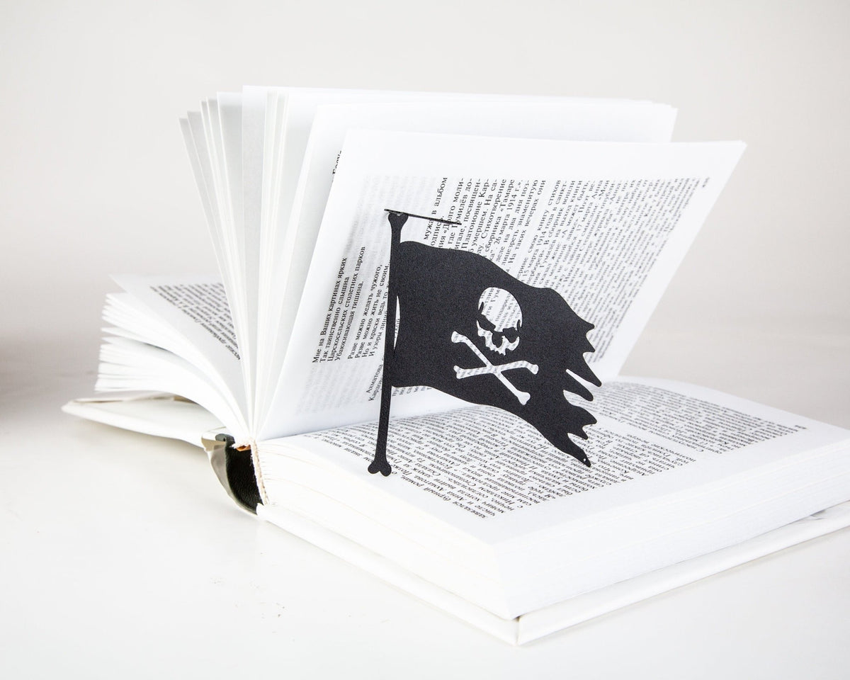 Jolly Rogers metal bookmark resting on the pages of an open book