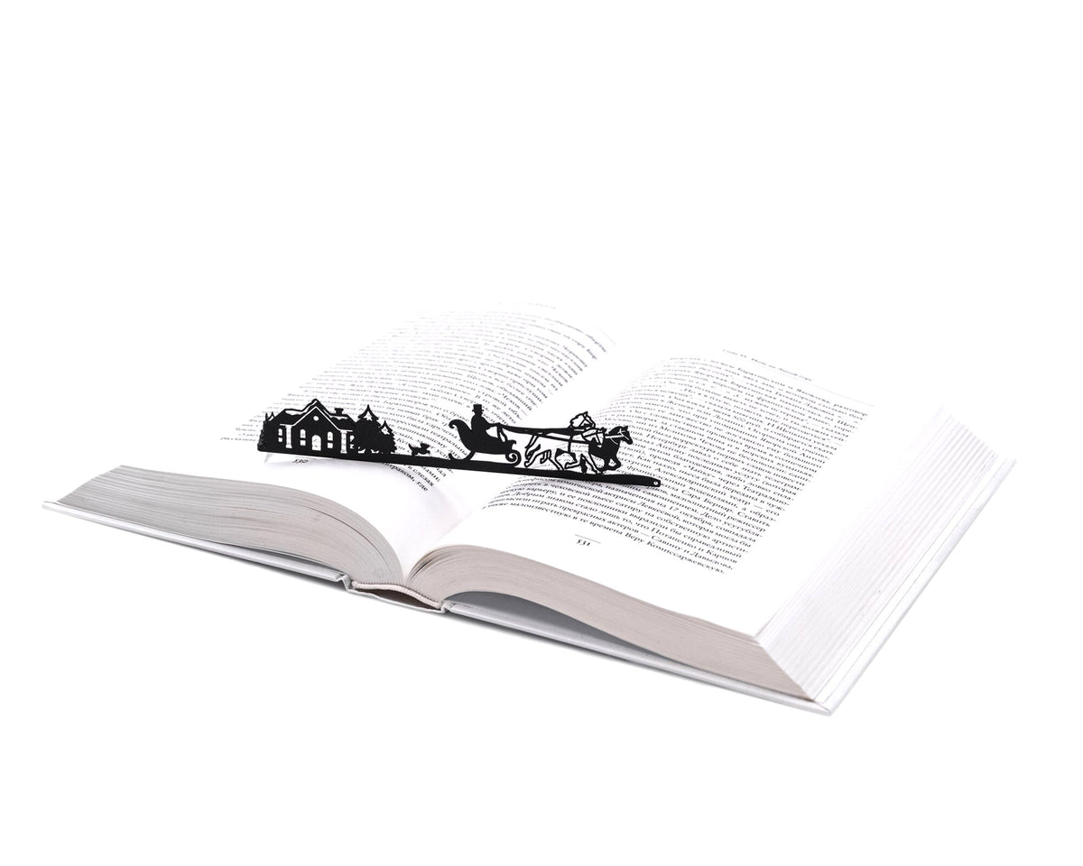 Winter Sleigh Ride metal bookmark resting on the pages of an open book
