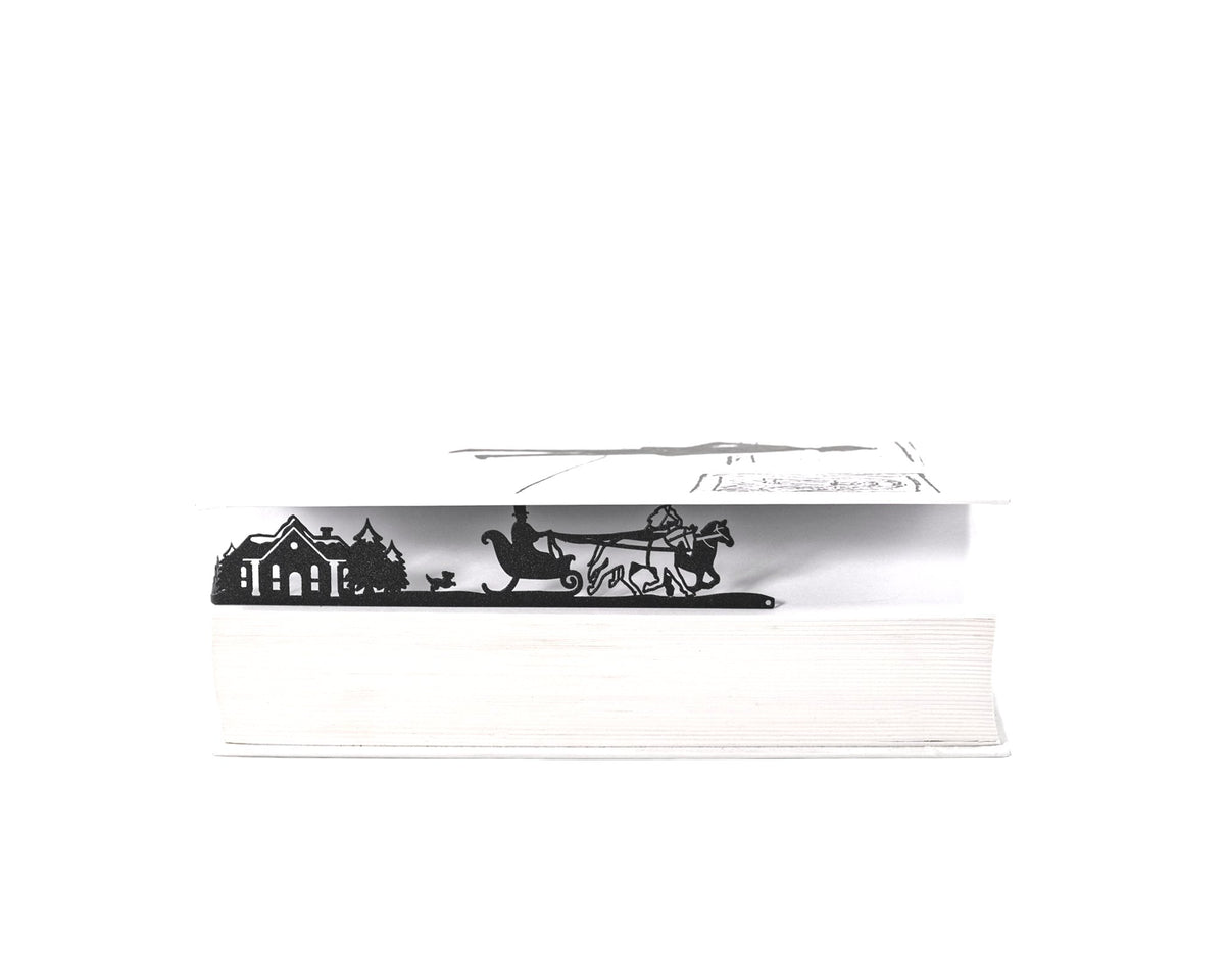 Winter Sleigh Ride metal bookmark clipped in a closed book, viewed from the side