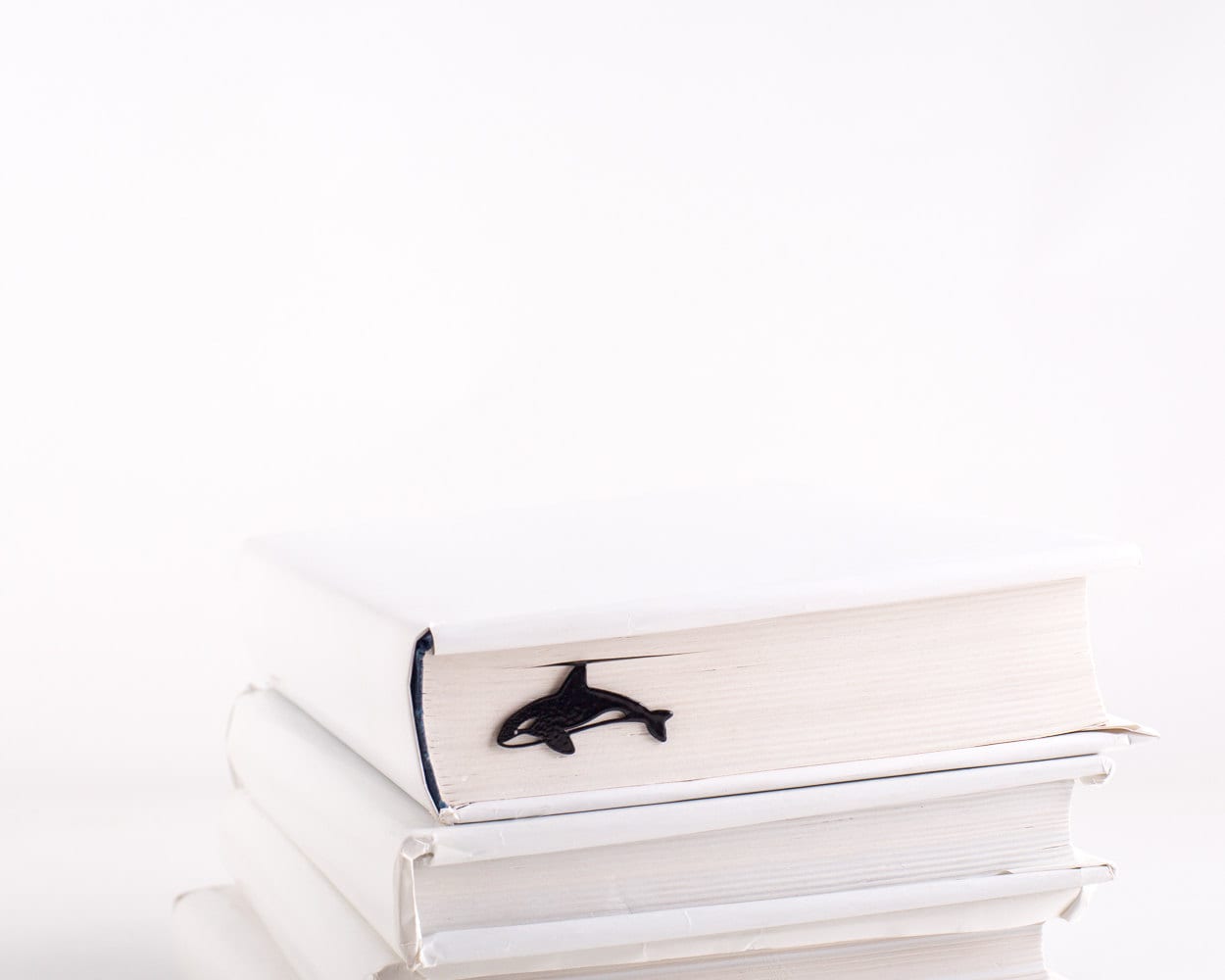 Killer Whale Orca metal bookmark shown with a stack of books