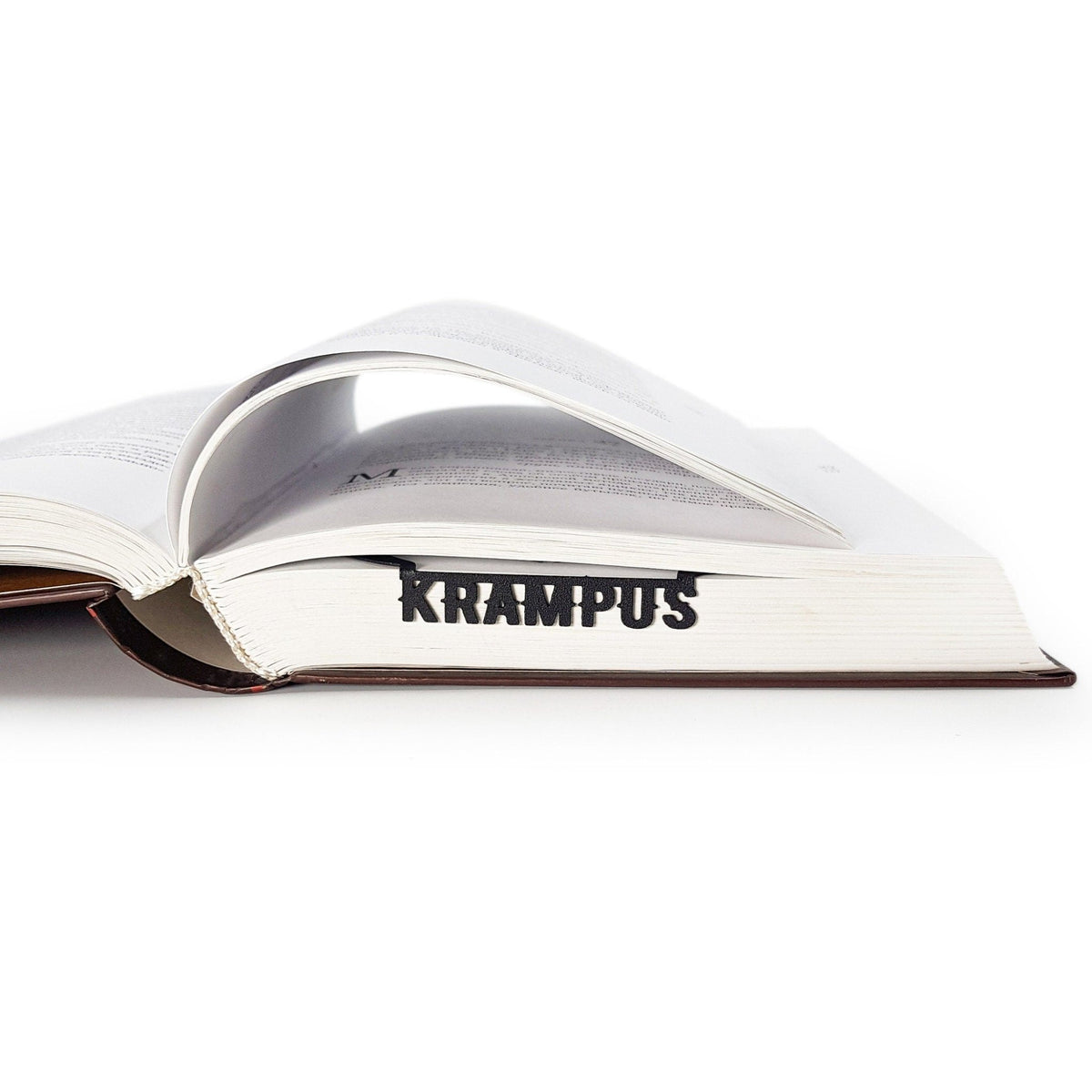 Krampus metal bookmark in a closed book, only its top showing above the pages