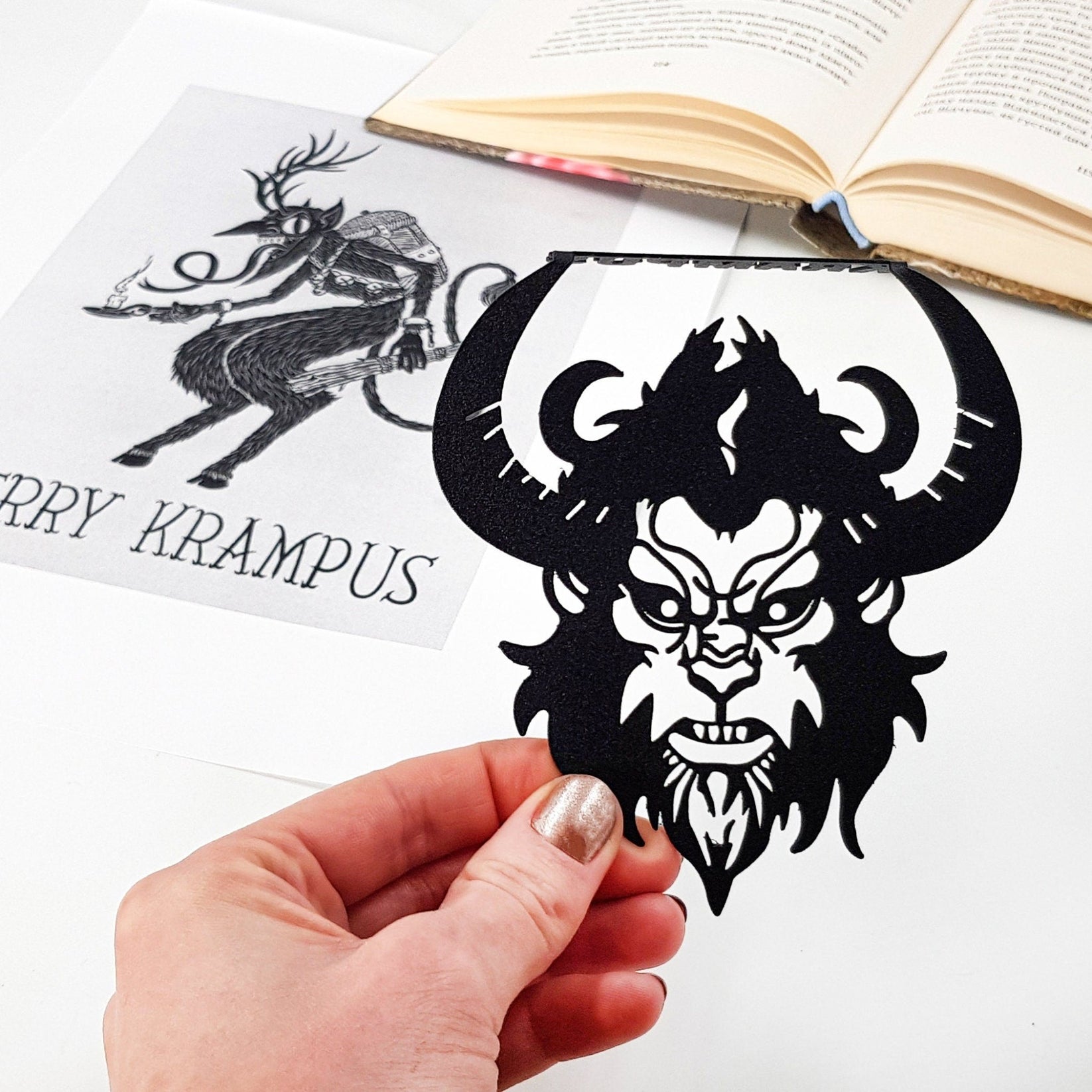 Krampus metal bookmark held in a hand to show its size