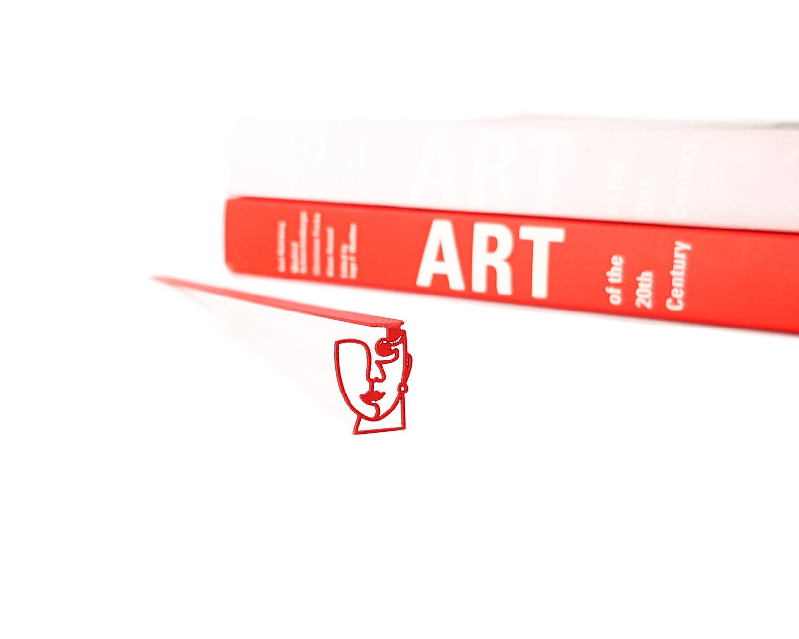 Lady in Red metal bookmark in red in a closed book, only its top showing above the pages