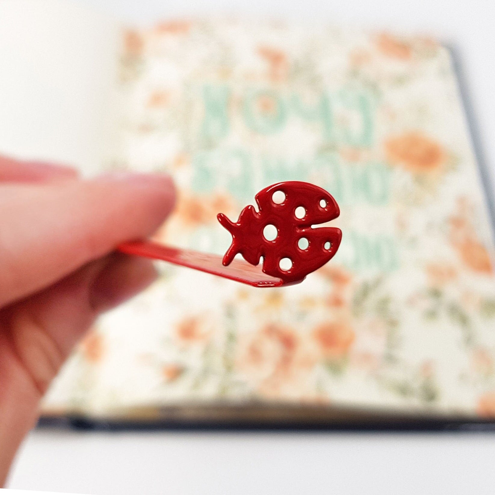 Ladybird metal bookmark in red against a coloured backdrop