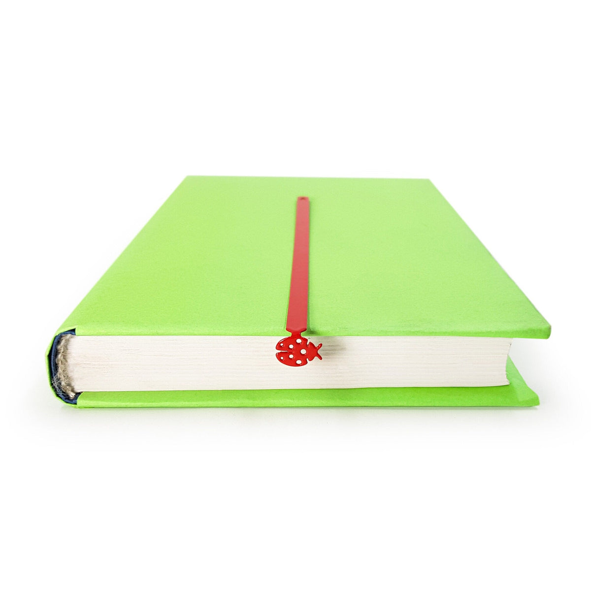 Ladybird metal bookmark in red in a closed book, only its top showing above the pages