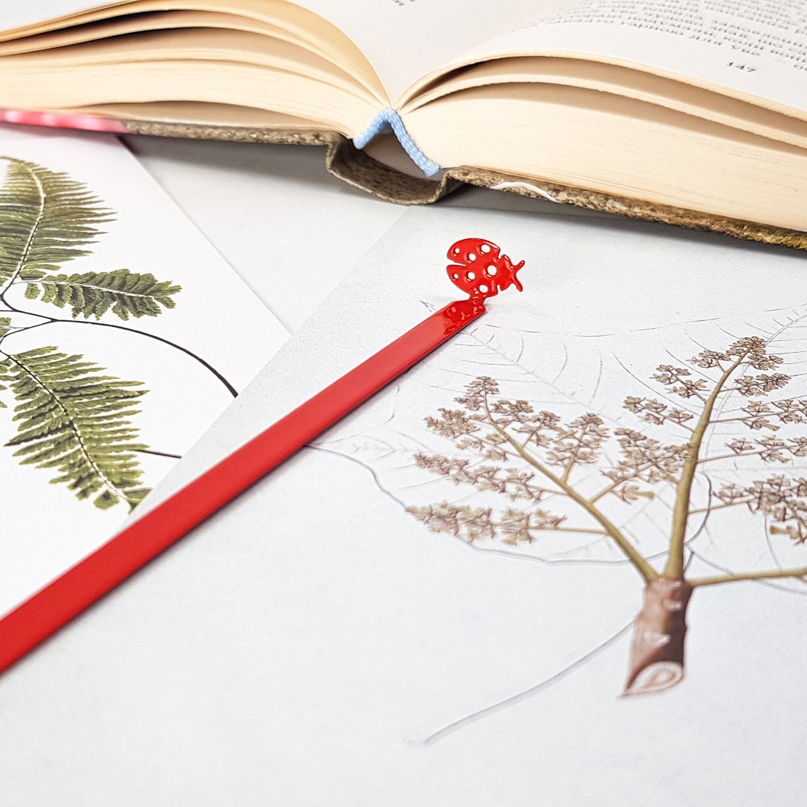 Ladybird metal bookmark in red marking a page in an illustrated book