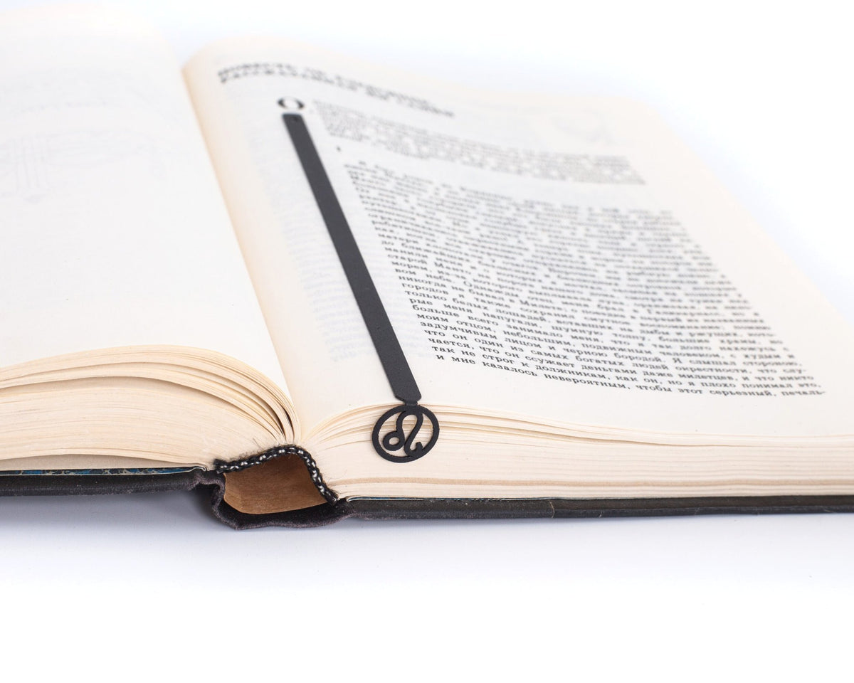 Leo metal bookmark marking a page in an open book