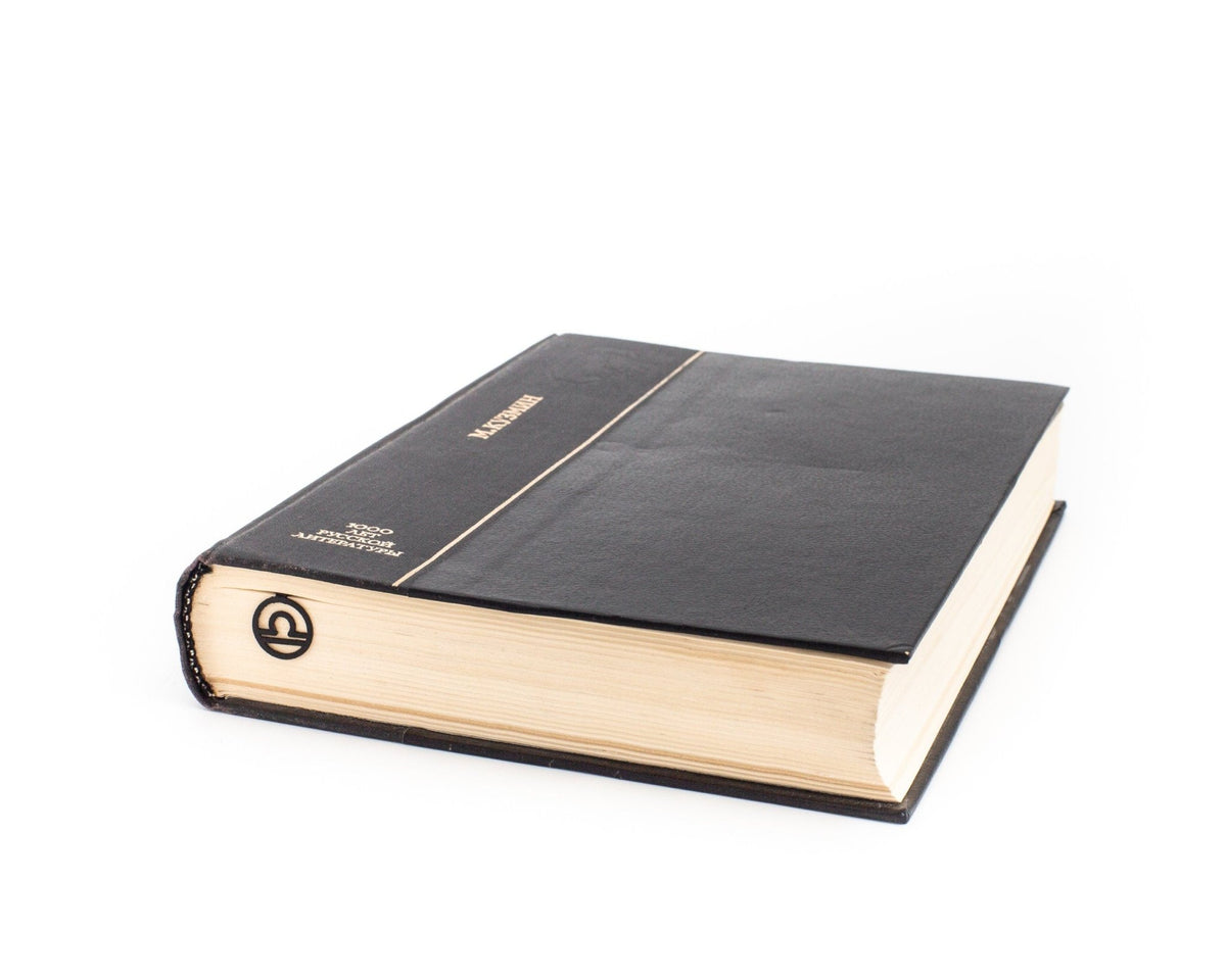 Libra metal bookmark in a closed book, only its top showing above the pages