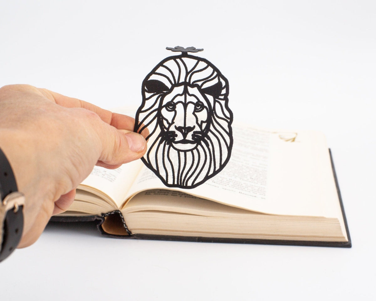 Lion Head metal bookmark held in a hand above an open book